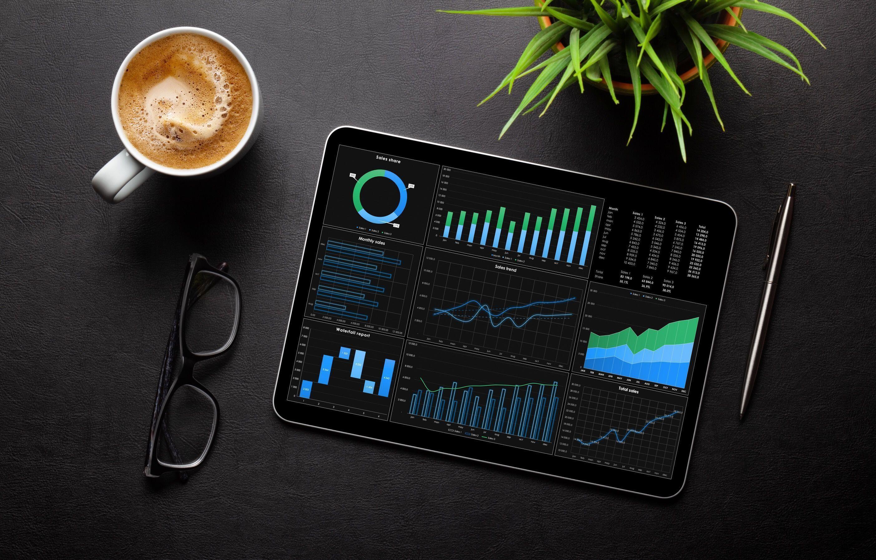 Datenanalyse auf Tablet Tablet mit Datenanalyse auf einem Tisch neben Kaffee und Stift