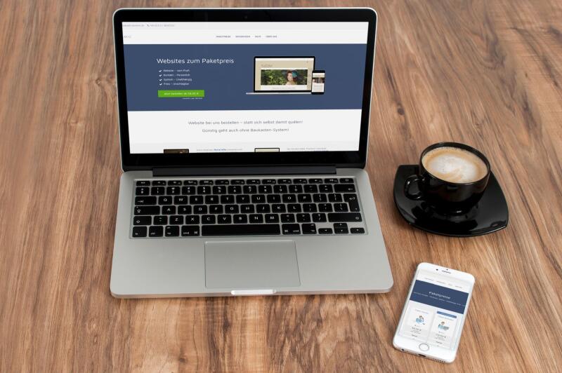 Laptop und Smartphone mit einer Webdynamik-Website auf einem Holztisch.